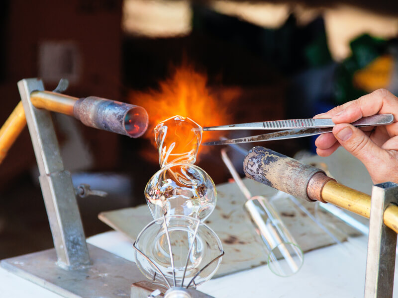 Someone makes glass art by doing glassblowing